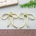 Pair of KC gold bow-shaped alloy pendants on a light grey background with measuring scale - Large Bowknot - KC Gold
