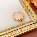 Nahaufnahme eines Vintage-Goldrings mit rotem Zirkon und grünem Emaille im Goldrahmen - Gold