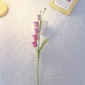 Handmade crochet lily of the valley bouquet in purple yarn on white fabric background - Single Stem Finished / Gradient Plum Red