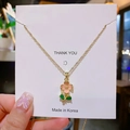 Collana a fiori dorata con petali rosa e foglie verdi su un supporto per gioielli - Fiore in Smalto Rosa