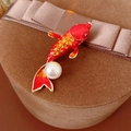 Detail of red enamel koi fish brooch with pearl on a velvet gift box background - Red