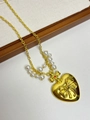 Detail of gold heart pendant with bow design, red gemstone and pearl accents - Gold Heart Bow Dimensional Gem