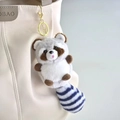 Detail van een schattige pluche wasbeer sleutelhanger met gestreepte staart op tas - Grijs