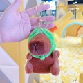 Plush brown capybara keychain featuring a green hood and golden metal clasp - Frog Hat Dark Brown + Gold Clip
