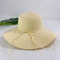 Detail of wide brim straw sun hat with ribbon bow decoration on white background - M (56-58cm) / Beige
