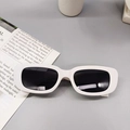 Flat lay of white narrow rectangular kids sunglasses with black UV lenses on magazine - Porcelain White