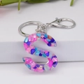 Letter S resin keychain featuring colorful crushed stones on a white display stand - Letter S