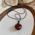 Detailed close-up of dark wood heart pendant on a display tray with natural linen textures - Dark Brown Heart