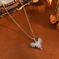 Vue détaillée du collier pendentif aile en argent avec zircons sur fond texturé élégant - Style Ailes Argentées