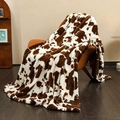 Cosy brown and white cow print faux rabbit fur blanket draped over a leather sofa chair - Coffee Cow