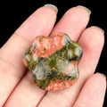 Unakite crystal cat paw stone carving held in hand for size visualization - Unakite
