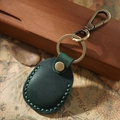 Detail of green leather AirTag holder with brass hardware and hand-stitched seams - Green