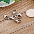 Five silver stainless steel lobster clasps on wooden surface with a reference coin - 10mm / Steel