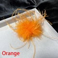 Detailed view of vibrant orange ostrich feather brooch on premium velvet display tray - Orange