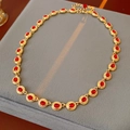 Detailed view of vintage gold necklace with red oval gemstone on grey velvet display - Necklace-Gold-Red