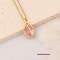 Gros plan du collier doré avec pierre rose en goutte et petits strass brillants - Tulipe