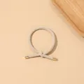 Close-up of beige ribbed hair tie with decorative knot and golden metal cylinder caps - Ribbed Knot - Metal Buckle / Beige
