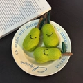 Three handmade green wool felt pear keychains with smiley faces on a ceramic plate - Offline Pear Trio