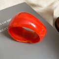 Primer plano de un anillo ancho de acrílico naranja translúcido con acabado brillante - Naranja