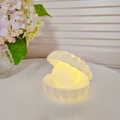 Shell and pearl shaped night light with soft warm yellow glow on a white desk - Small Shell White