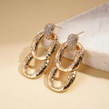 Gros plan détaillé de boucles d'oreilles ovales dorées avec zircon et texture martelée - Doré