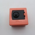 Close-up of orange plastic money box with black combination lock dial and hinges - Tan