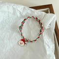Detailed macro view of Christmas bracelet with Santa charm, bell, and red green woven cord - Christmas Red Hat