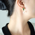 Orecchini pendenti dorati con zircone verde e perla a goccia bianca indossati da una modella - Oro Verde Smeraldo