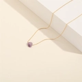 Detailed shot of amethyst heart pendant on a gold chain over minimalist white steps - Amethyst