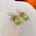 Détail de boucles d'oreilles papillon avec cristaux dégradés jaune-vert sur plateau céramique - Vert