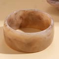 Detailed top view of a wide resin bangle with amber marble texture on warm matte background - Wide Round Style / Off-White Marble Pattern