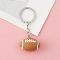 Miniature brown American football keychain with realistic white stitching on pink background - Silver Chain Style-Rugby