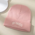 Roze gebreide muts met wit Los Angeles borduursel op een stijlvol beige oppervlak - Eén maat / Roze