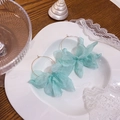 Dettaglio di orecchini a cerchio con fiori in tessuto azzurro su vassoio bianco - Blu