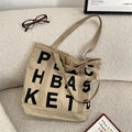 Macro detail of khaki canvas tote bag with black letter print and reinforced handles - Khaki