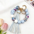 Detail eines Silikon-Perlenarmbands mit Blumenmuster, blauer Lederquaste und Goldring - Blau Blumig