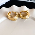 Detailansicht unregelmäßiger goldener Creolen mit Metallic-Finish auf einem Tablett - Gold