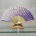 Traditional Chinese folding fan featuring purple cherry blossom gradient with silk tassel - Flower Clusters (Purple)