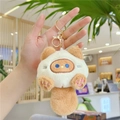 Close-up of plush cat keychain with blue eyes and gold metal clip on a backpack - Gold Lobster Clasp / Brown and White Patchwork