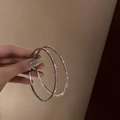 Macro detail of large silver hoop earrings with shimmering rhinestones held by hand - Large / Silver