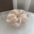 Macro view of champagne satin hair scrunchie with rhinestones on a glass tray - Apricot