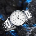 Primer plano de un reloj de cuarzo de acero plateado con esfera blanca sobre piedra - Esfera blanca con números arábigos