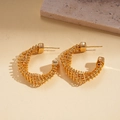 Detail of 24k gold-plated twisted C-shaped earrings with spiral metallic texture on a stone - Spiral Textured C-Shape Style / Gold