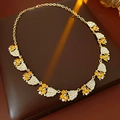 Detalle de collar vintage dorado con hojas y cristales sobre almohadilla de cuero - Dorado/Blanco/Naranja