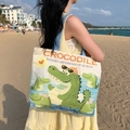 Off-white canvas tote bag with blue straps and crocodile print shown on sunny beach - Sunglasses Crocodile