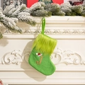 Green knit Christmas stocking with golden letter J and red Santa hat on a cozy fireplace - Letter J