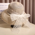 Elegant Audrey Hepburn style straw sun hat with a large white lace bow and pearl trim - Beige