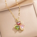 Detail van gouden ketting met klaverhanger van rode, groene en roze hartvormige stenen - Gouden Ketting / Goud