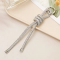 Close-up of luxury silver rhinestone knot keychain charm on an elegant beige display tray - Knot Rhinestone Chain Pendant / White