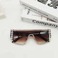 Détail rapproché de lunettes de soleil oversize avec strass et verres dégradés marron sur tissu - Monture Noire Verres Thé